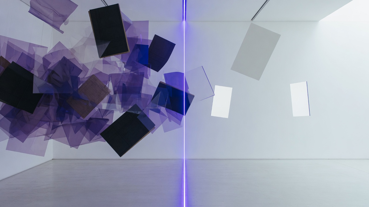 Gallery installation: dense translucent sheets on one side, sparse white planes on the other, split by a vertical indigo line