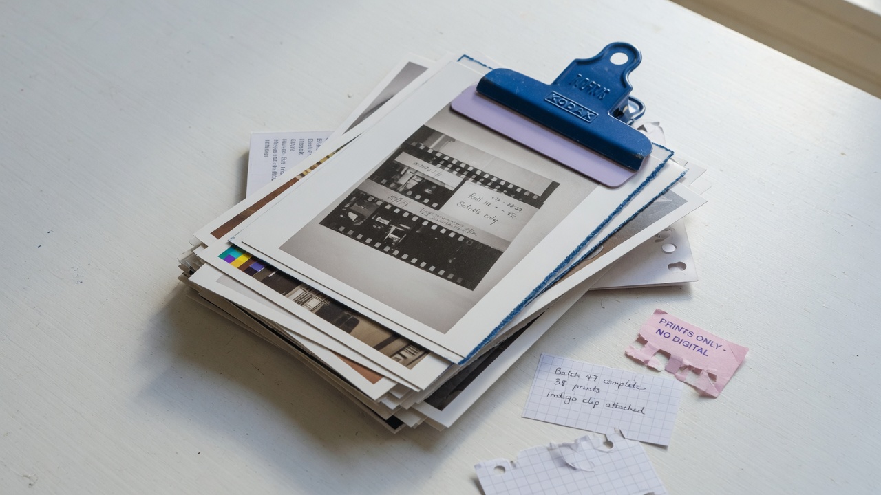 Stack of photographic prints clipped with an indigo edge on a white table