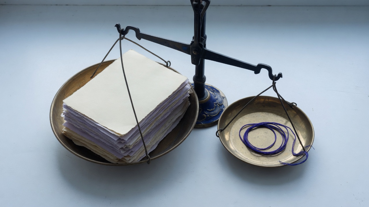 Balance scale with paper stack and indigo thread